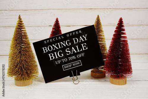 Festive display with small decorative Christmas trees with "Special Offer Boxing Day Big Sale up to 70% off, Promotion Holiday Sale Event