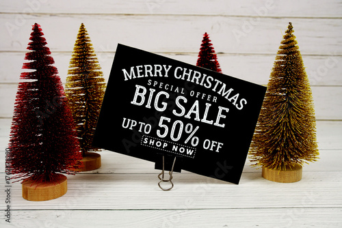 Festive display with small decorative Christmas trees with "Special Offer Merry Christmas Big Sale up to 50% off, Promotion Holiday Sale Event