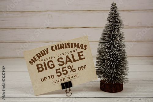Festive display with small decorative Christmas trees with "Special Offer Merry Christmas Big Sale up to 55% off, Promotion Holiday Sale Event