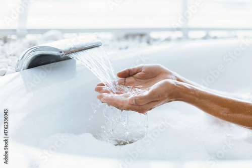 Fotografie Hands cupped under a soothing stream of water flowing from a modern fixture