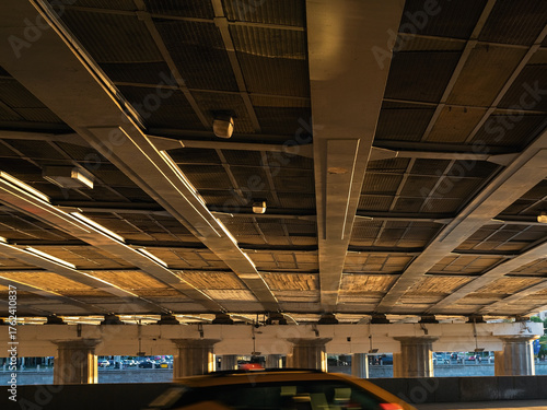 under a wide road bridge in the evening, roofs of moving cars, selective focus