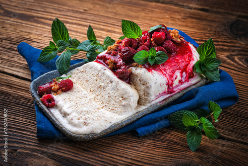 Homemade french parfait - frozen dessert with whipped cream fresh, raspberries and peppermint served as close-up on a plate