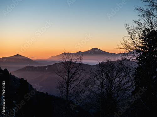 Winter mountain landscape, snowy peaks on sunset with fog

