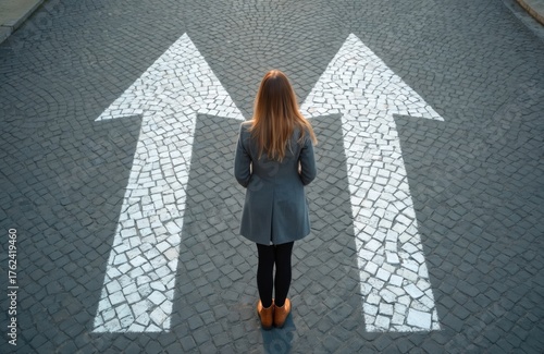 Woman stands at crossroads with two arrow signs pointing forward. She ponders which path to choose, symbolizing decision making. Future options appear before her on the street.
