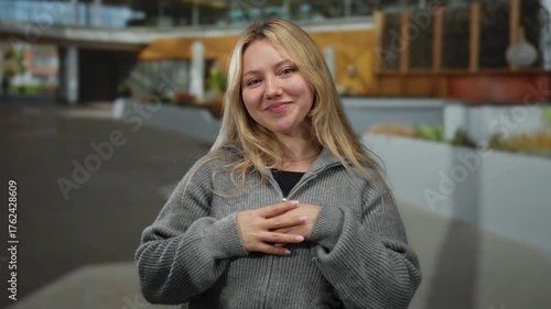 Wallpaper Mural Young blonde woman smiling playfully on a city street in casual attire, showcasing expressions of happiness and connection in an urban outdoor setting. Torontodigital.ca