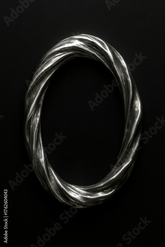 Twisted silver oval sculpture on black background
