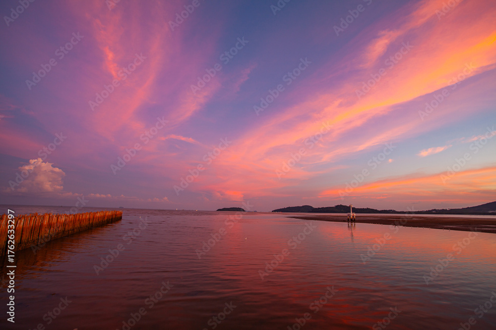 Fototapeta premium The tranquil lake reflects the fiery hues of sunset, where orange, pink, and violet merge into calm waters. Gentle ripples shimmer beneath a peaceful sky capturing the serene beauty of nature.