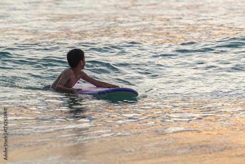Wallpaper Mural  A young surfer rides with confidence and excitement, enjoying the calm waves of a tropical beach. The warm hues of sunset reflect on the ocean, blending energy, motion, and carefree joy. Torontodigital.ca
