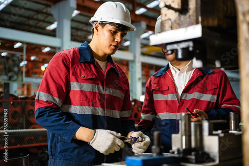 Fotografie Engineering instructor guiding apprentice in machine operation during industrial training at manufacturing plant