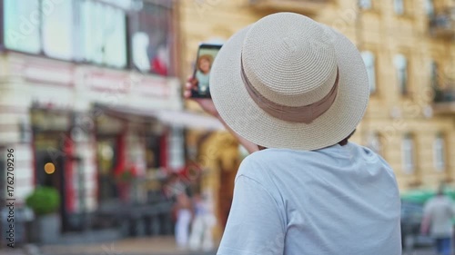Young student tourist in straw hat back view taking selfie on phone capturing travel impressions about ancient old city on vacation