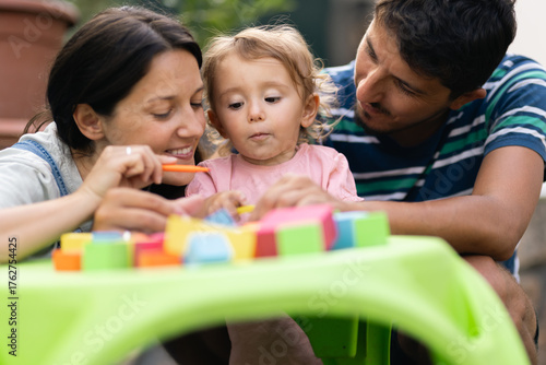 Parents engaging with their child in playful learning activities outdoors