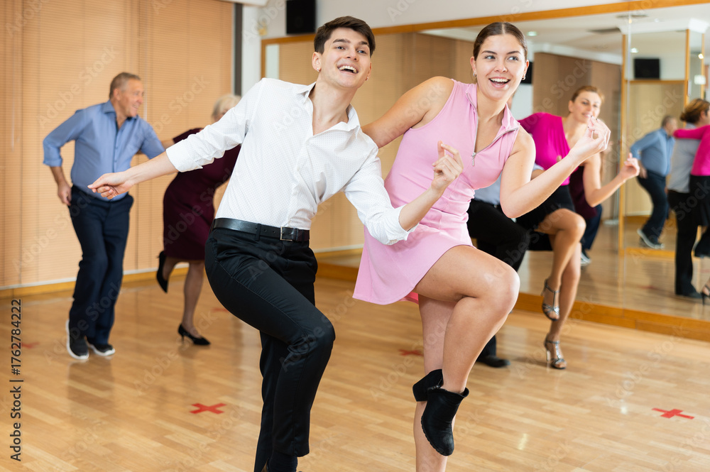 Fototapeta premium Active young pair practicing Latino dance in training hall during dancing-classes. Pairs training ballroom dance