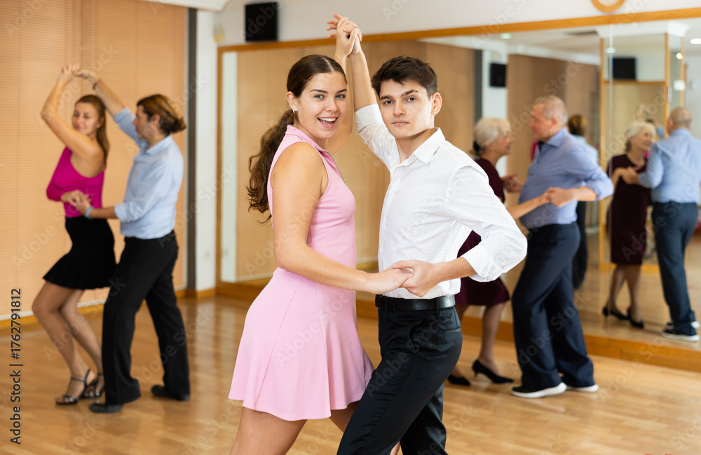 Naklejka premium Cheerful young couple practicing passionate samba in dance class. Amateur dancing concept..