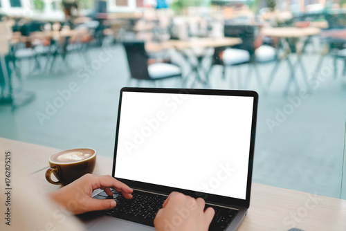 Wallpaper Mural A person working on a laptop with a blank screen at a window counter, overlooking an outdoor cafe patio, with a cup of coffee. Torontodigital.ca