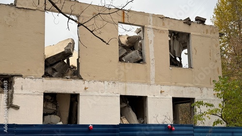 Foto Abandoned building under partial demolition with blue metal fence and debris, ur