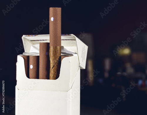 Open white pack of brown cigarillos on a dark blurred background, showing detailed texture and rich tones, symbolizing luxury smoking products and tobacco craftsmanship.