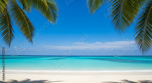 Idyllic tropical beach with white sand, crystal clear turquoise water, and lush green palm leaves framing the perfect blue sky