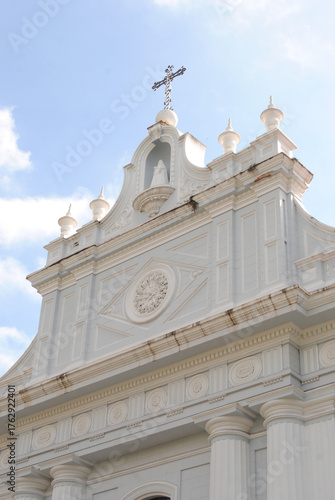 Fachada de iglesia blanca con cruz bajo un cielo despejado