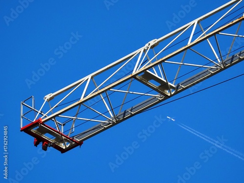 Construction Crane Arm and Airplane in Clear Blue Sky
