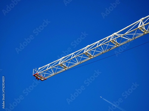 Construction Crane Arm and Airplane in Clear Blue Sky