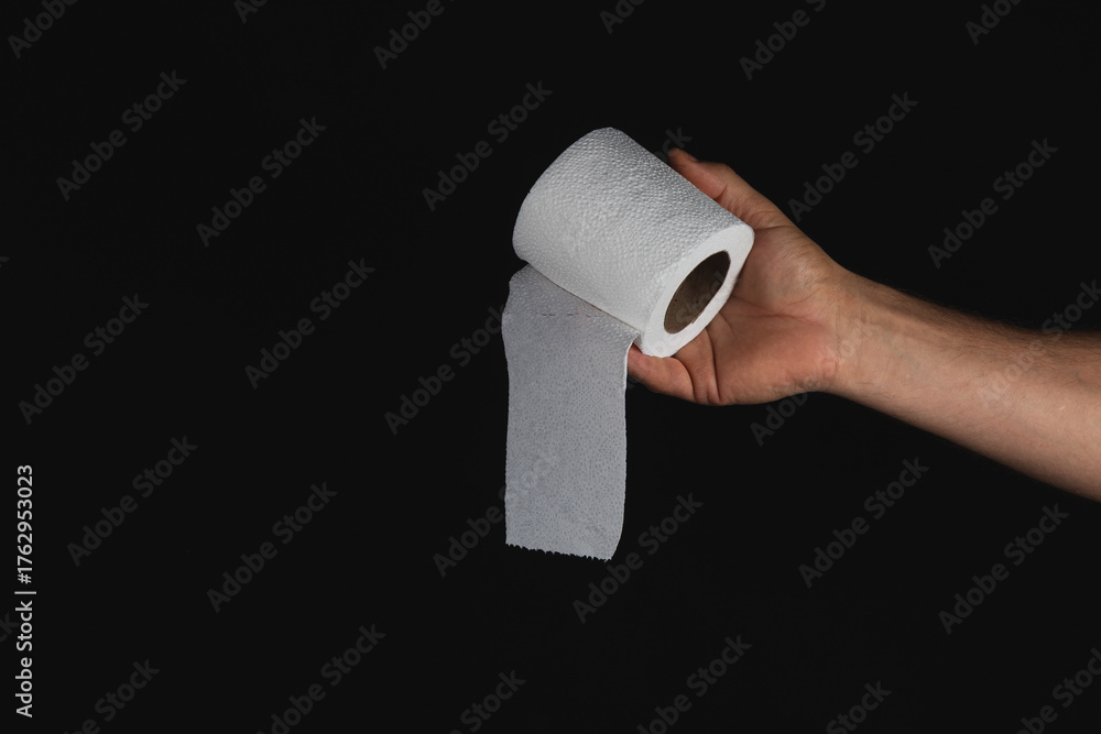 Obraz premium Hand holding roll of grey paper towel against black background