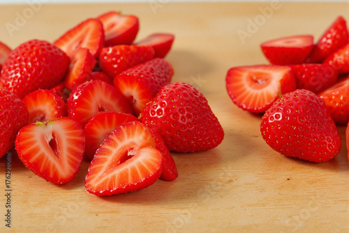Freshly sliced strawberries arranged on wooden cutting board  