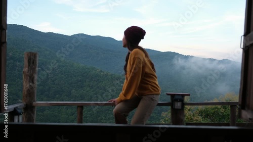 Blurred of a woman sitting on wooden balcony with mountain views on foggy morning