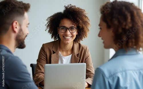 Curly haired caucasian woman is having a business discussion while holding her laptop and looking through eyeglasses. High quality