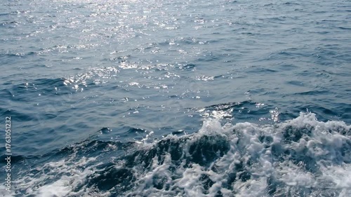 Dark blue and white ocean waves form diagonal lines on the sea surface, with fine white foam contrasting against the rippling water, demonstrating the power and movement of the ocean.