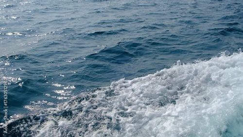 Dark blue and white ocean waves form diagonal lines on the sea surface, with fine white foam contrasting against the rippling water, demonstrating the power and movement of the ocean.