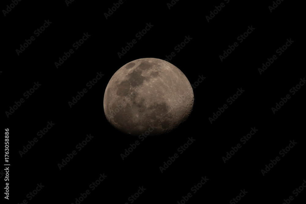 Obraz premium Imagen astronómica de la Luna en fase gibosa creciente, mostrando detalles de su superficie, cráteres y mares lunares sobre un fondo negro.