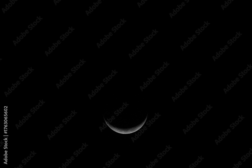Obraz premium Luna en fase creciente sobre fondo negro. Fotografía de la Luna en fase creciente capturada en la noche, mostrando solo una fracción iluminada sobre un fondo negro profundo.