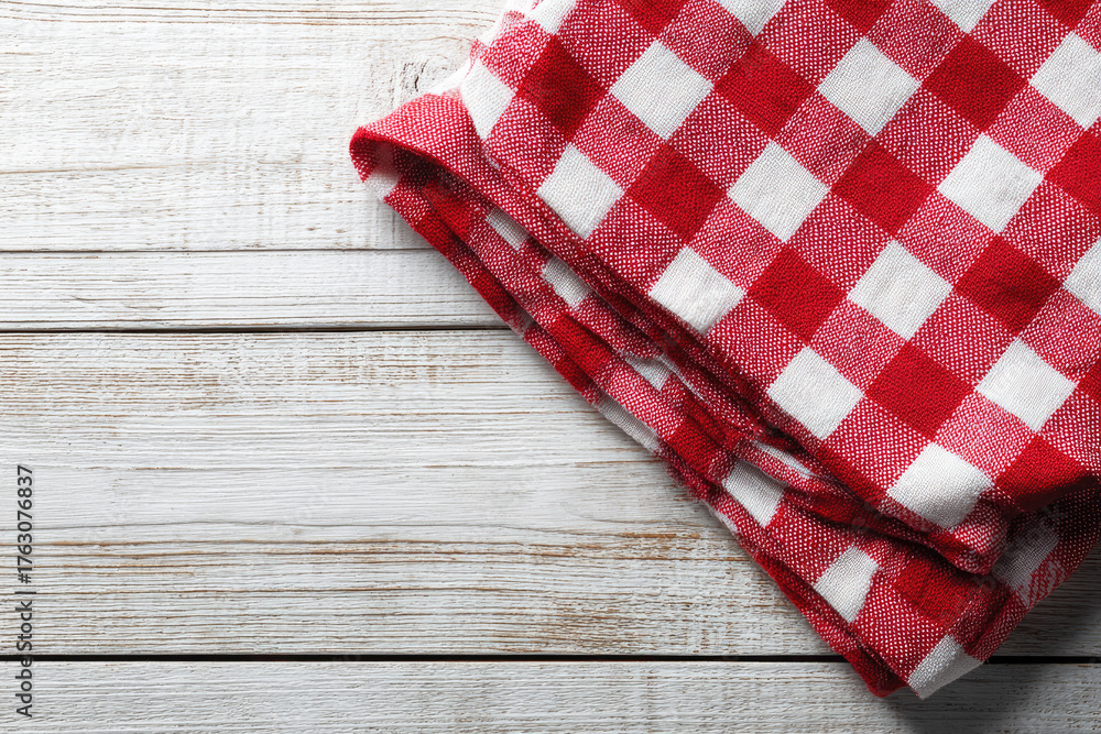Obraz premium Red checkered tablecloth on white wooden table background, top view, copy space.