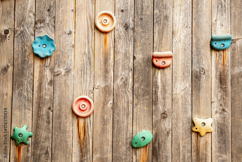 Colored climbing holds on a wooden wall in a children's playground