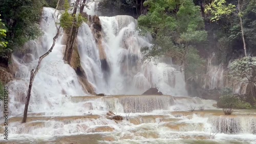 waterfall cascading through lush tropical jungle, surrounded by mist and greenery. The powerful flow of water creates a tranquil and awe-inspiring natural scene in untouched paradise