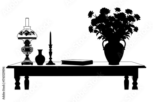 Elegant silhouette of a table display featuring a large vase of flowers a lamp a candle holder and a book