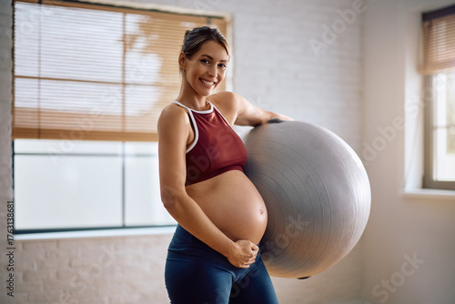 Obraz na plátně Happy pregnant woman with fitness ball during prenatal exercise class looking at camera