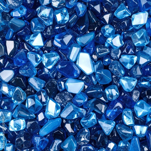 A vibrant pile of shimmering blue glass shards glistens under soft light, showcasing various shapes and sizes, creating an artistic, textured display.