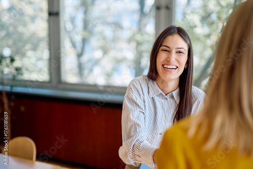 Obraz na płótnie Two businesswomen having a cheerful conversation in a modern office, enjoying a