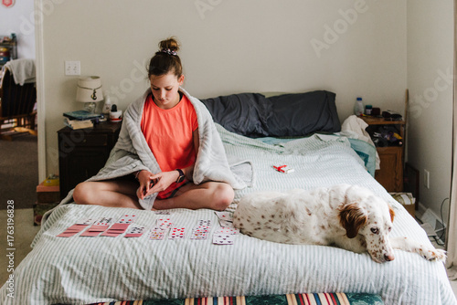 Girl playing solitaire while her dog sleeps next to her