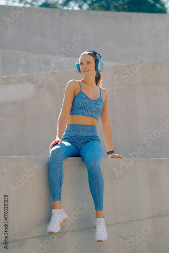 Outdoor workout session with a young athlete in a blue sports outfit, enjoying music