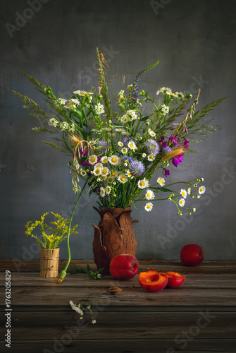 Still life with a bouquet of meadow flowers and ripe and sweet fruits.