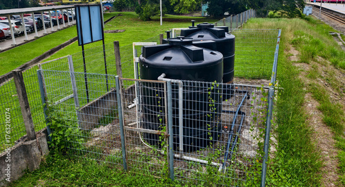 Two large black polyethylene water tanks,  for a rainwater harvesting system. These tanks are designed to collect and store rainwater for various uses. 