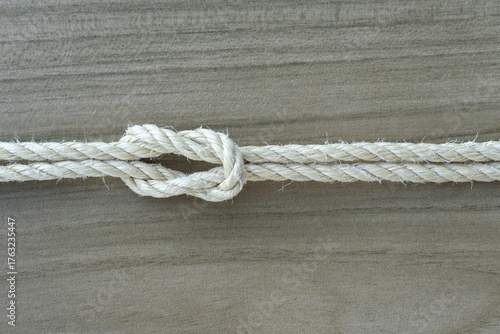 Close-up of a tied rope knot on light wood background, symbolizing trust, stability, connection, and teamwork. Ideal for conceptual visuals in business, nature, or cooperation themes.