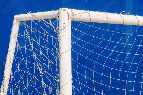 Close-up of a soccer goal net on a blue background.