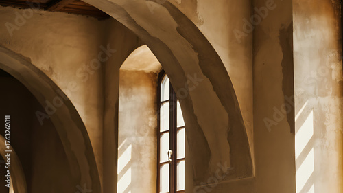 Sunlight streams through arched windows illuminating textured walls in an old building