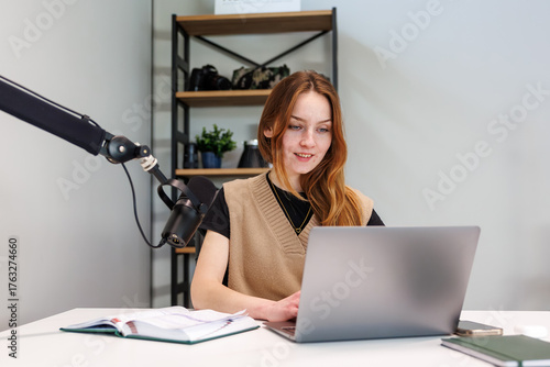 Cuadro en lienzo A young woman types at a laptop beside a condenser mic on a boom arm