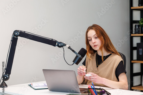 Cuadro en lienzo Creator demonstrates earbuds at a modern desk, speaking into a branded microphone on a boom arm beside a laptop