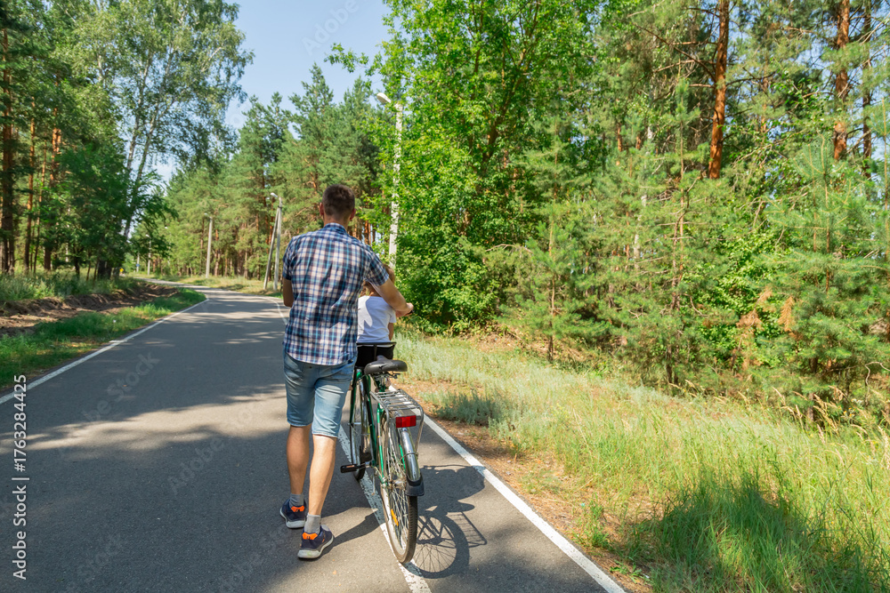 Obraz premium Young father with his little daughter on bicycle in summer sunny forest