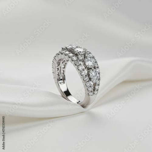 Close up of a platinum diamond ring with multiple rows on a white silky background